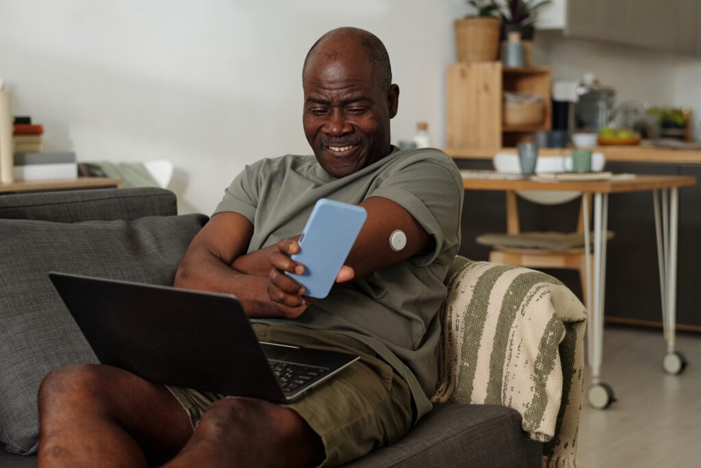 elderly african american man smiling while checking his smartphone CGM