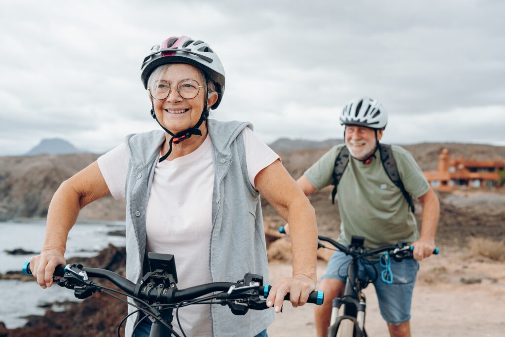 senior couple riding bikes together in rocky beach